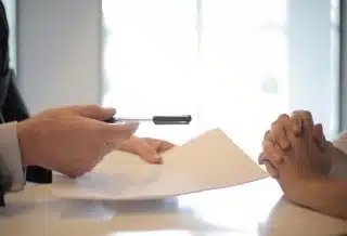 Crop businessman giving contract to woman to sign