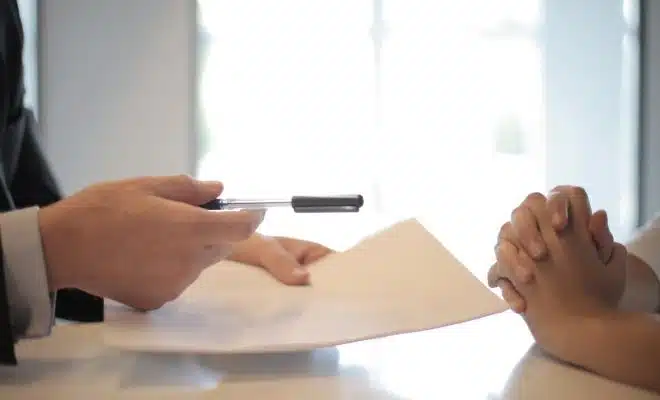 Crop businessman giving contract to woman to sign