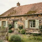 Petite maison en pierre avec jardin privatif à louer dans le Puy-de-Dôme, façade traditionnelle auvergnate avec volets verts et portail en bois